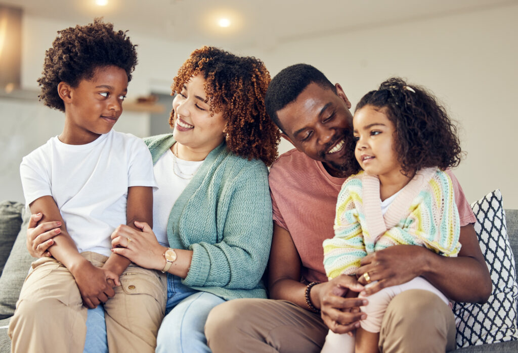 A family sitting on a couch having a family meeting to discuss screen time boundaries and "tech rules" together.
