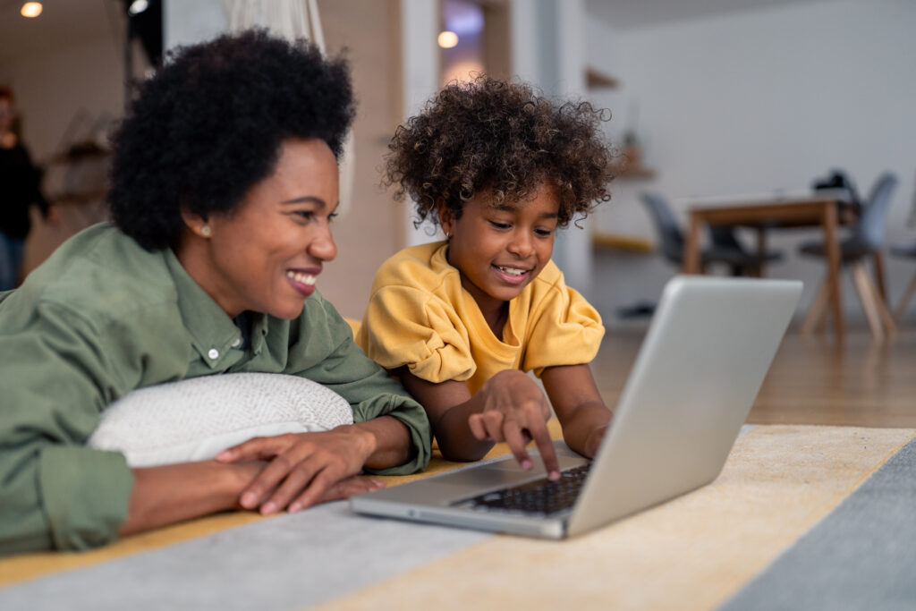 A mother and son sitting behind a computer writing and designing a story together.