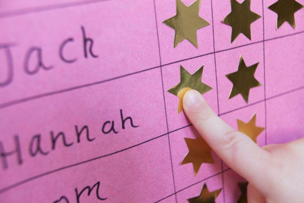 close-up of a child adding a sticker to a hand-made chart