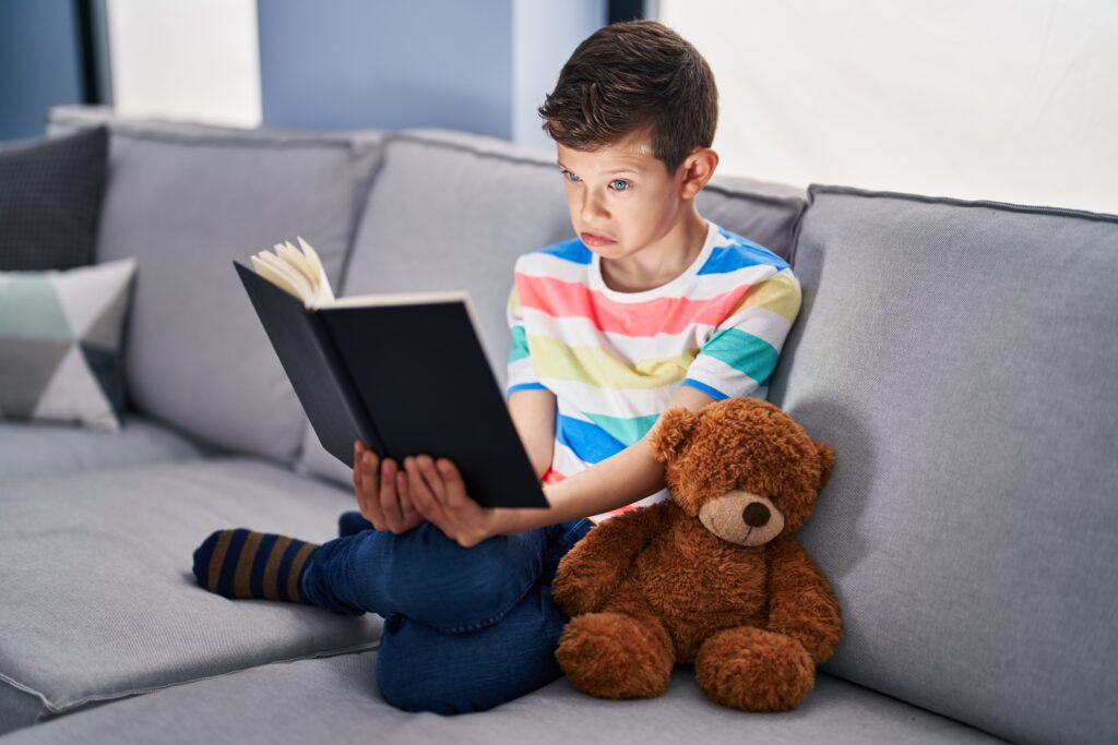 9-year-old boy holding a book with an unsure expression.