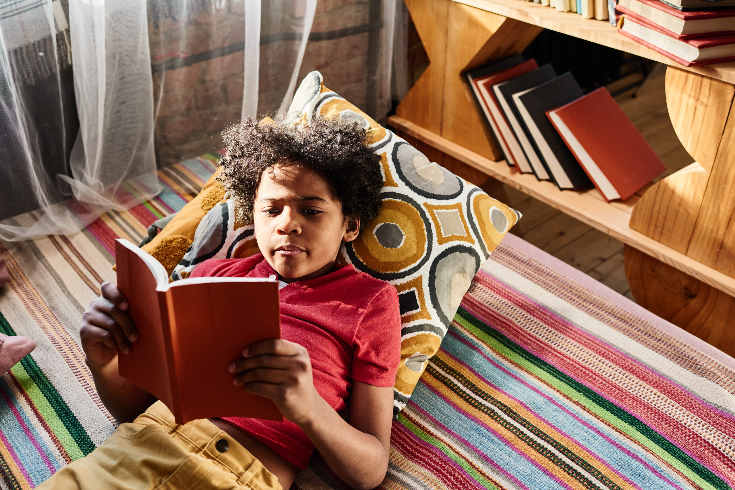 Kid happily reading in a simple book nook.